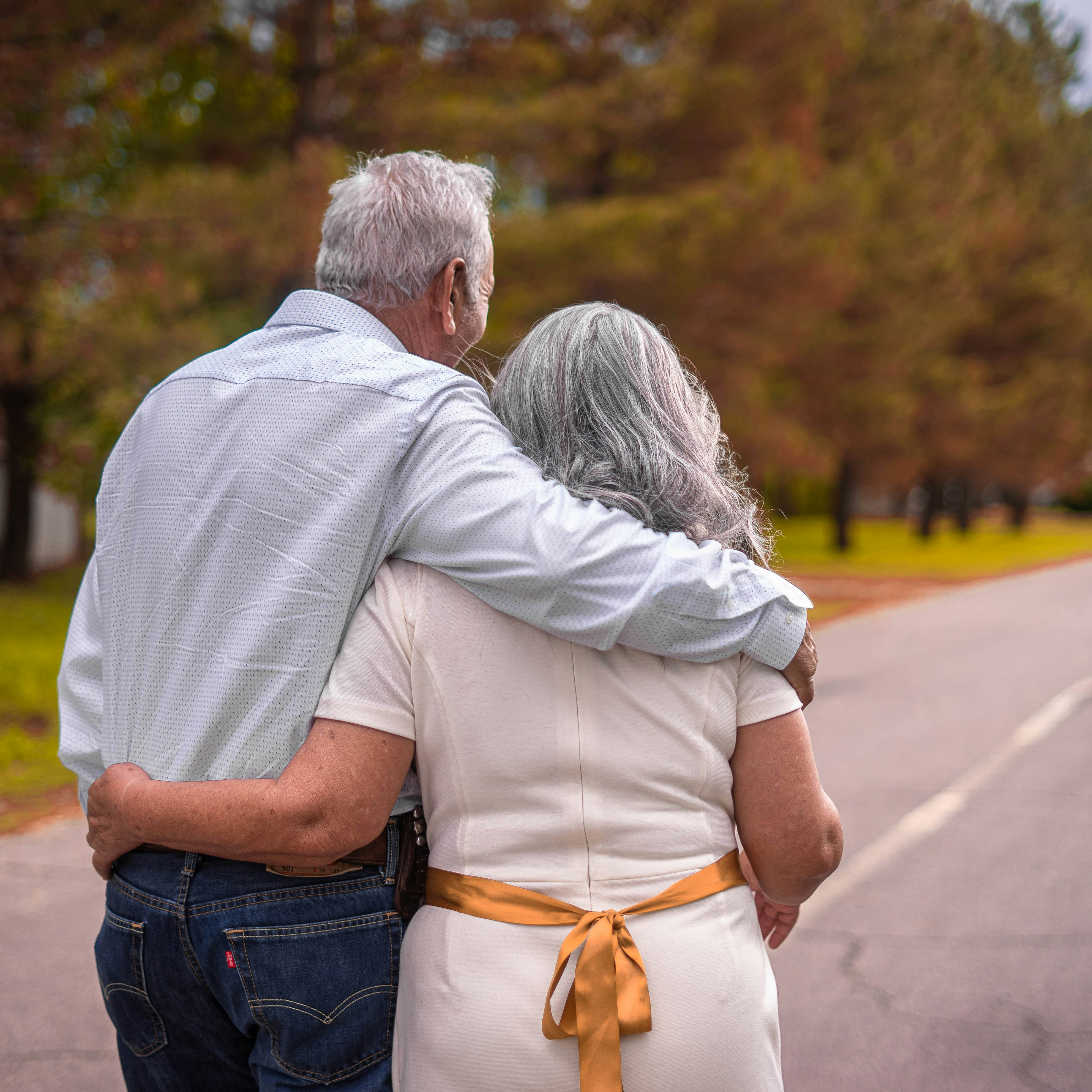 older couple embracing as they walk on a fall day.